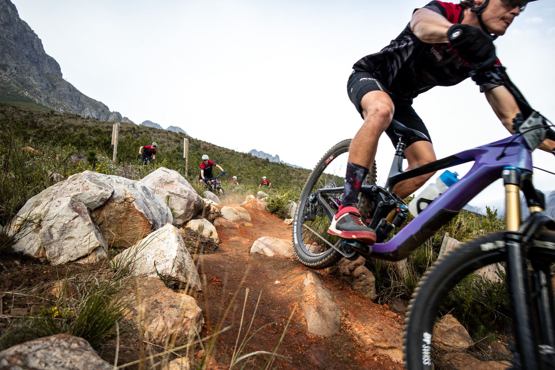 An academy rider cornering through a rock garden above Stellenbosch